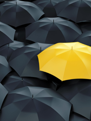 Unique yellow umbrella among many dark ones. Standing out from crowd, individuality and difference concept.